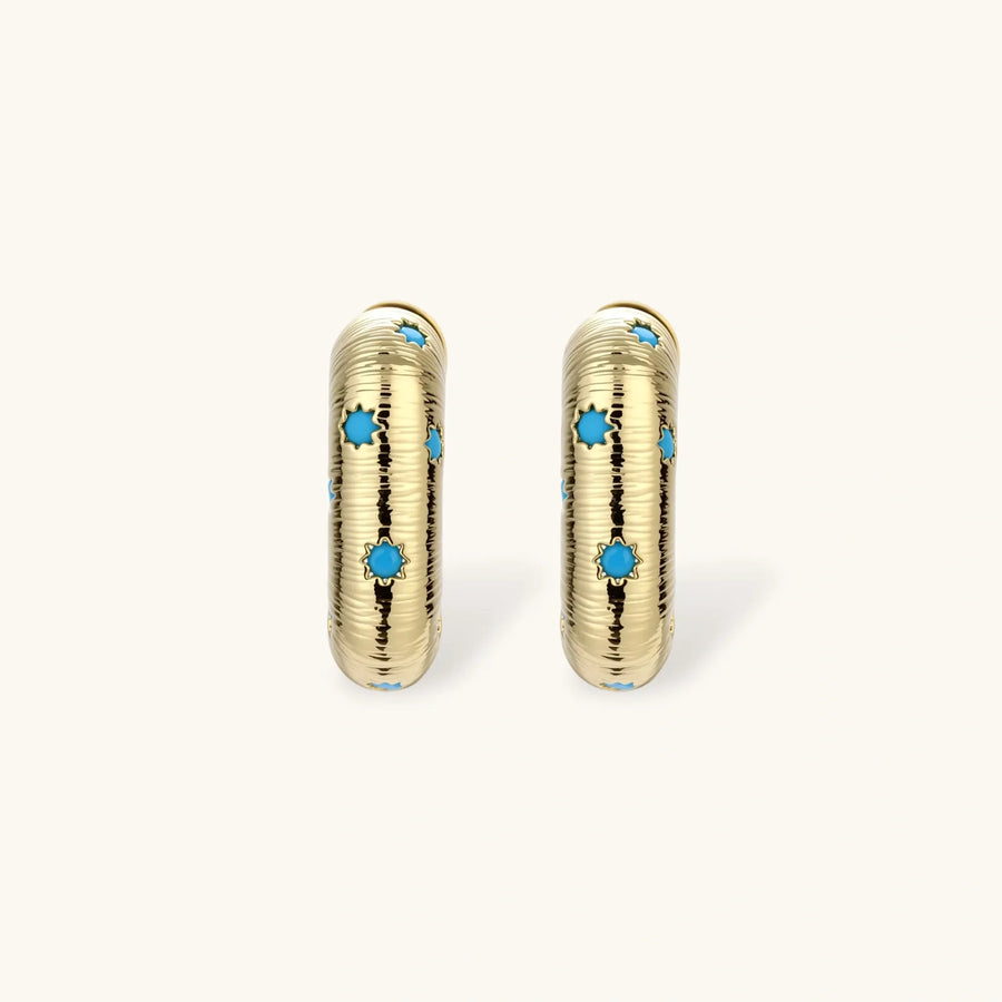 Gold-plated huggie hoop earrings with blue star inlays and textured surface, shown against white background.