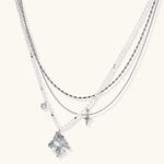 Multi-strand layered necklace set with silver chains, white pearls, star charm, heart pendant, and ornate decorative piece