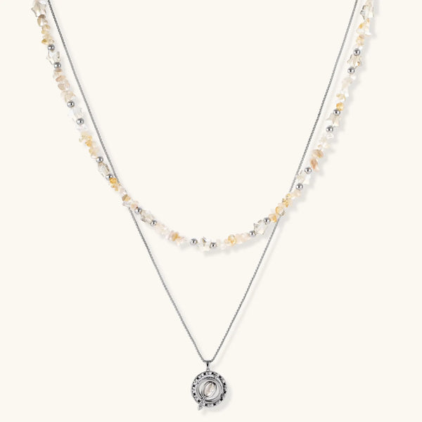 Two-layer necklace with natural stone chips and eco-brass beads, featuring a circular wrapped pendant on cream background.