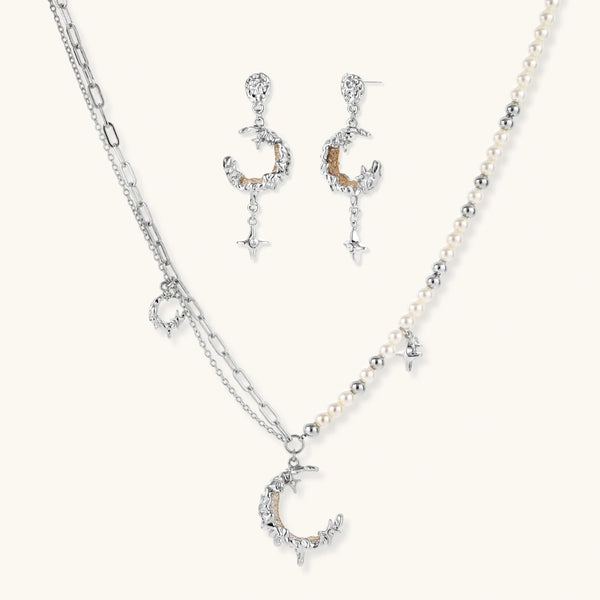 Mixed-metal jewelry set featuring layered necklaces with crescent moon pendant and pearl beads, plus matching star-drop earrings.