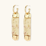 Cylindrical bar earrings featuring speckled natural resin center with polished metal caps and lever-back closures