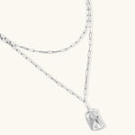 Silver layered necklace with organic flowing pendant in eco-zinc alloy on neutral background, showing adjustable chain design.