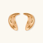 Pair of gold crescent moon-shaped stud earrings with textured surface details on cream background.
