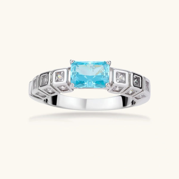 Geometric silver-plated ring with rectangular aqua cubic zirconia center and square crystal details on adjustable band.